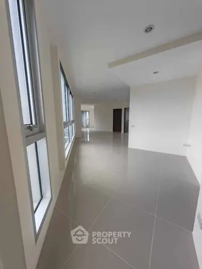 Spacious modern living area with large windows and glossy tiled flooring