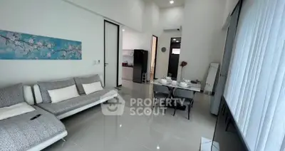 Modern living room with sleek furniture and open kitchen layout in a bright apartment.
