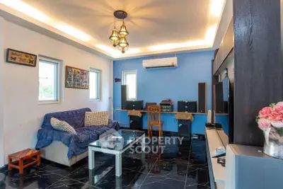 Stylish living room with modern decor and blue accent wall, featuring sleek black flooring and elegant lighting.