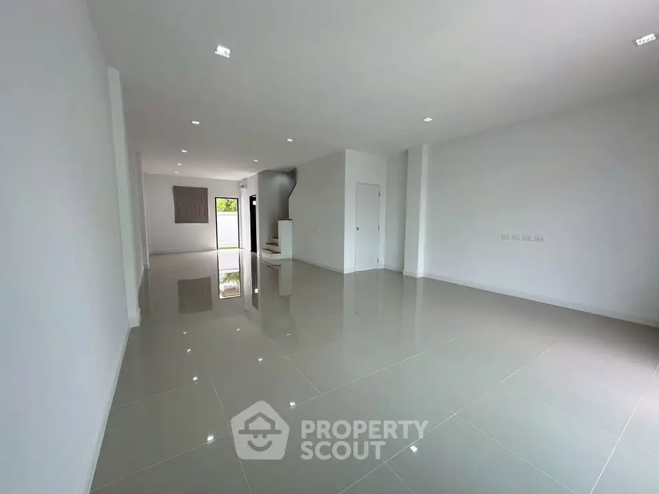 Spacious modern living room with glossy tiled floors and ample natural light.