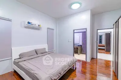 Spacious bedroom with modern design and wooden flooring, featuring a comfortable bed and ample natural light.