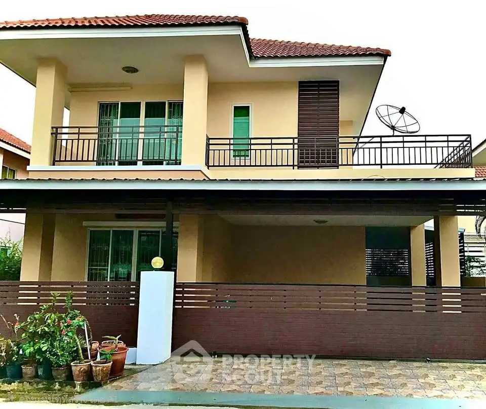 Charming two-story house with balcony and satellite dish, featuring a modern design and spacious outdoor area.