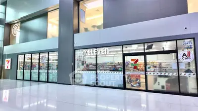 Modern commercial retail space with glass facade in a bustling shopping center.