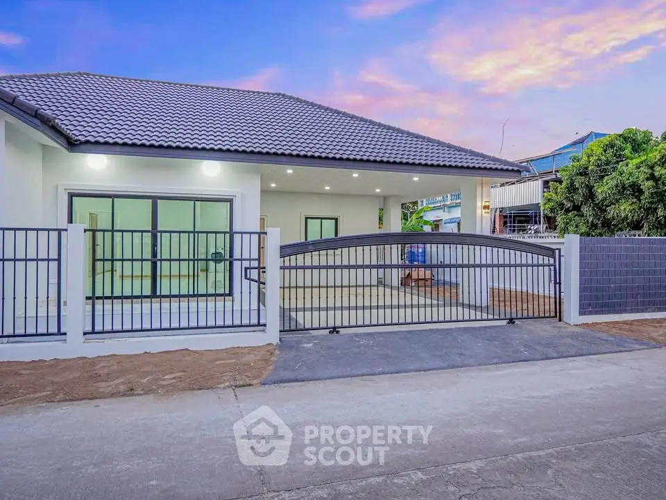 Charming single-story home with modern fence and spacious driveway at sunset.