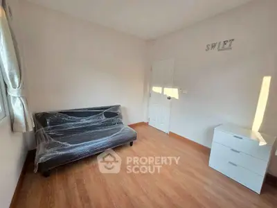 Minimalist room with wooden flooring, sofa, and chest of drawers, perfect for cozy living.