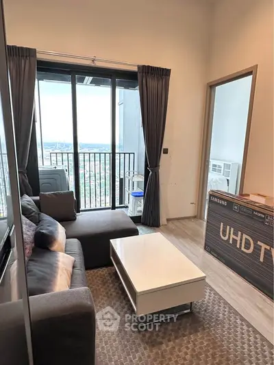 Modern living room with balcony view and stylish furniture in high-rise apartment.
