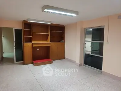 Spacious room with built-in wooden shelves and glass door entry