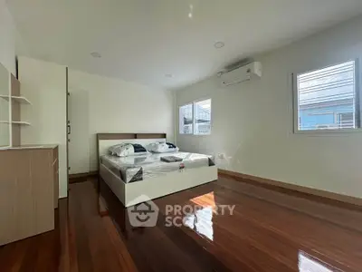 Spacious bedroom with wooden floors and modern air conditioning unit, perfect for comfort and relaxation.