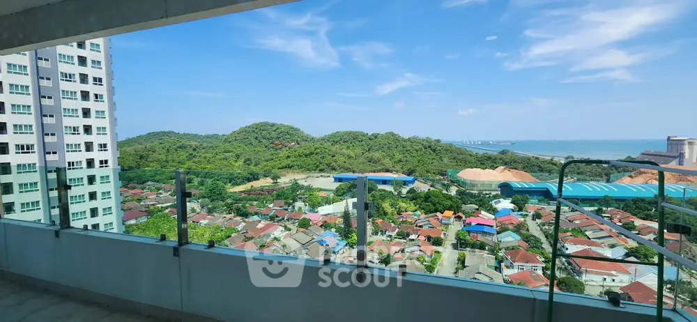 Stunning high-rise balcony view overlooking lush green hills and vibrant cityscape.