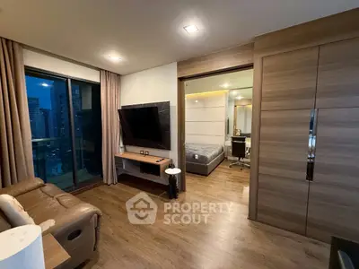 Modern living room with wooden flooring, large TV, and city view balcony in a stylish apartment.