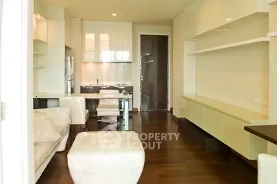 Modern living room with sleek white furniture and open kitchen layout