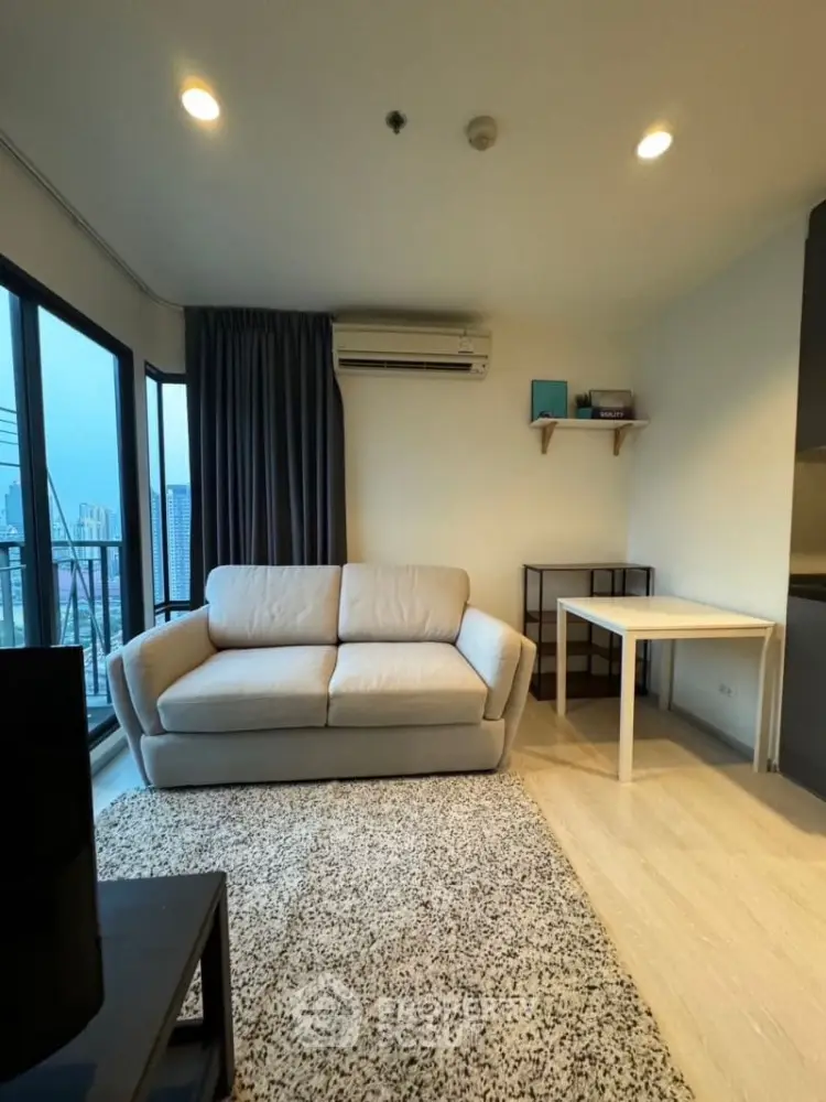 Modern living room with city view, cozy sofa, and stylish decor in a high-rise apartment.