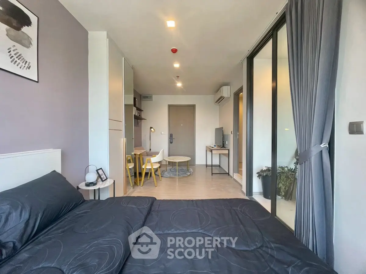 Modern studio apartment with stylish decor and open layout, featuring a cozy bed and dining area.