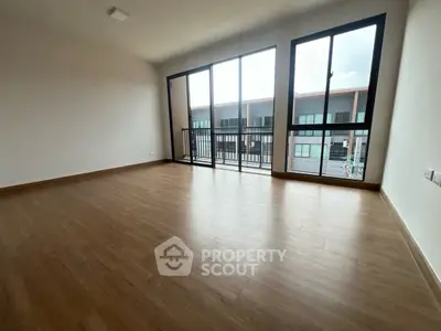 Spacious empty room with large windows and wooden flooring, ideal for customization.