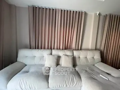 Luxurious living room with plush white sofa and elegant curtains, perfect for relaxation.