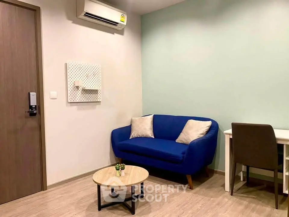 Cozy living room with blue sofa, desk, and air conditioning in modern apartment.