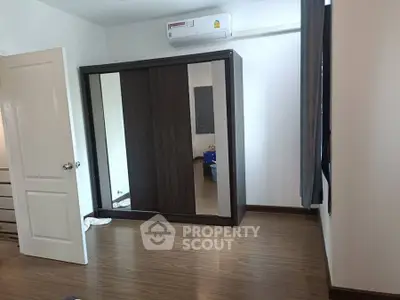 Spacious bedroom with wooden flooring and large mirrored wardrobe