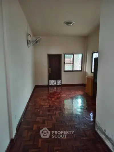 Spacious room with wooden flooring and natural light, ideal for versatile living space.
