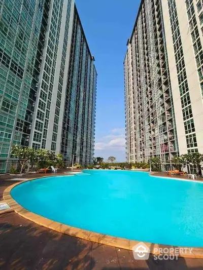 Luxurious high-rise apartment buildings with a stunning outdoor pool and clear blue sky.