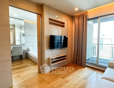 Modern living room with wooden flooring, TV, and balcony access in a stylish apartment.