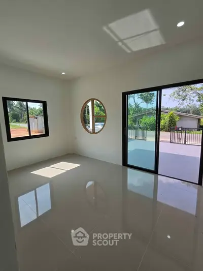 Bright living room with unique round window and sliding glass doors opening to a patio.