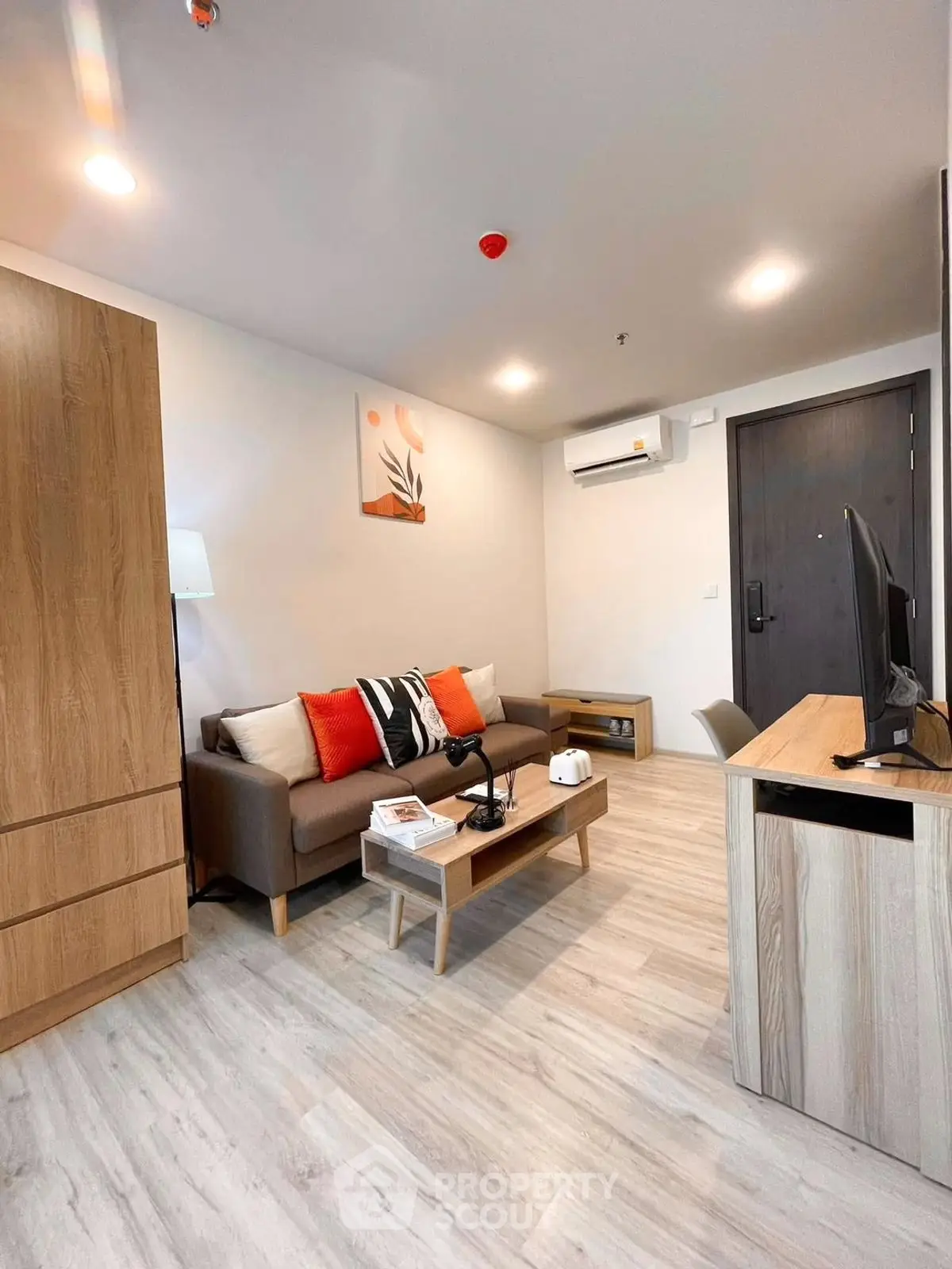 Modern living room with stylish decor and wooden furniture, featuring a cozy sofa and flat-screen TV.