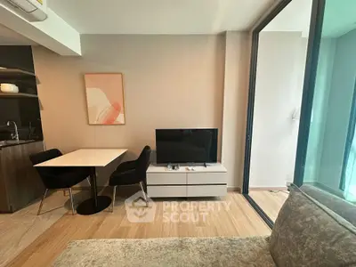 Modern living room with sleek furniture and large glass doors opening to a balcony.