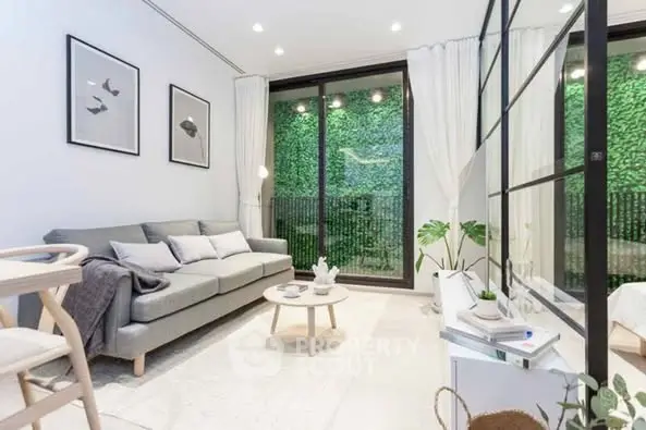 Modern living room with large windows and lush green view, stylish decor and cozy ambiance.