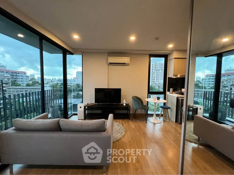 Modern living room with large windows and city view, featuring stylish furniture and open layout.