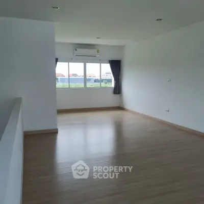 Spacious empty room with large window and wooden flooring, perfect for customization.