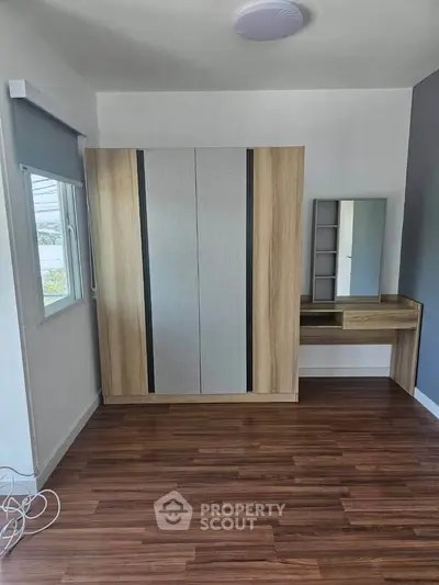 Modern bedroom with sleek wardrobe and vanity on polished wooden floor.