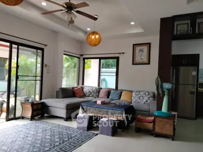 Spacious living room with modern decor and large windows overlooking a lush garden.