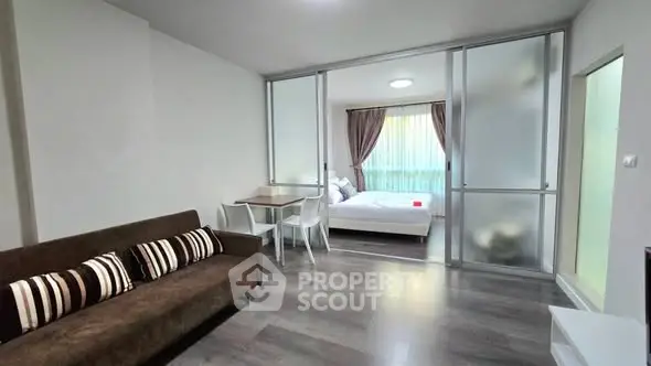 Modern studio apartment with glass partition, cozy living area, and stylish bedroom.