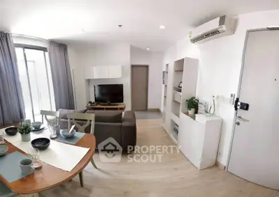 Modern living room with dining area, featuring sleek furniture and natural light.