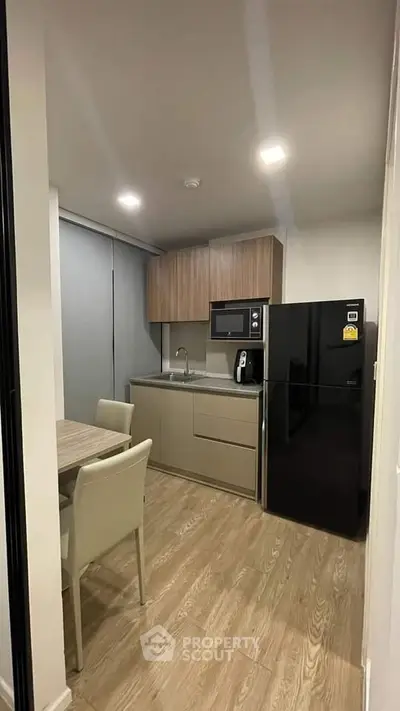 Modern kitchen with sleek cabinetry and dining area in cozy apartment.