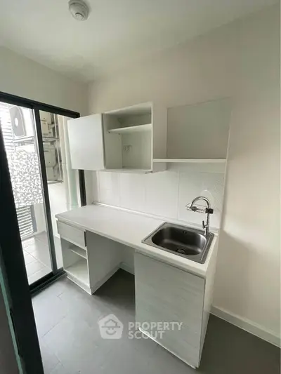 Compact kitchen with sleek white cabinetry and stainless steel sink, perfect for modern living.