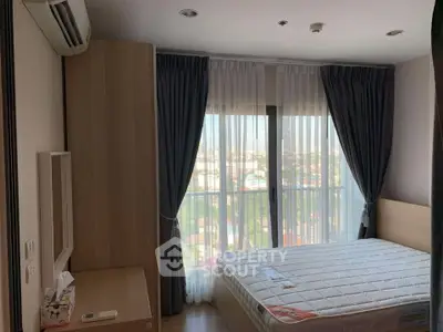 Cozy bedroom with large window and modern furnishings in a high-rise apartment.