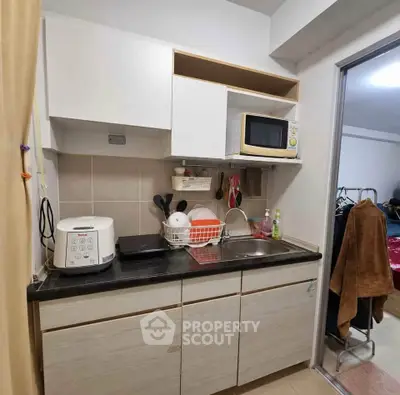 Compact kitchen with modern appliances and open shelving in cozy apartment.