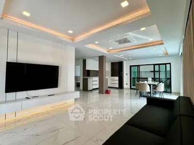 Luxurious modern living room with sleek design and open layout, featuring a large TV and elegant lighting.