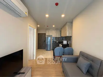 Modern open-layout living room with kitchen, featuring sleek furniture and appliances, perfect for urban living.