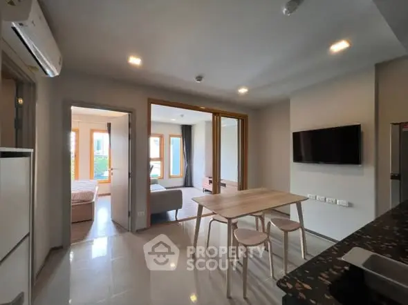 Modern open-plan living area with dining table and wall-mounted TV