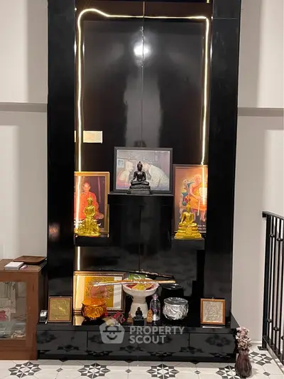 Elegant home altar with religious statues and framed artwork, featuring sleek black design and ambient lighting.