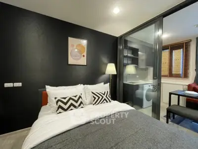 Modern bedroom with stylish decor and adjacent kitchen featuring washing machine and dining area.
