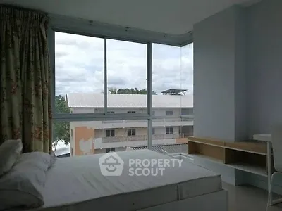 Spacious bedroom with large windows offering a serene view of the neighborhood.