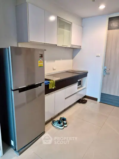 Modern kitchen with sleek cabinets and stainless steel fridge in a compact apartment