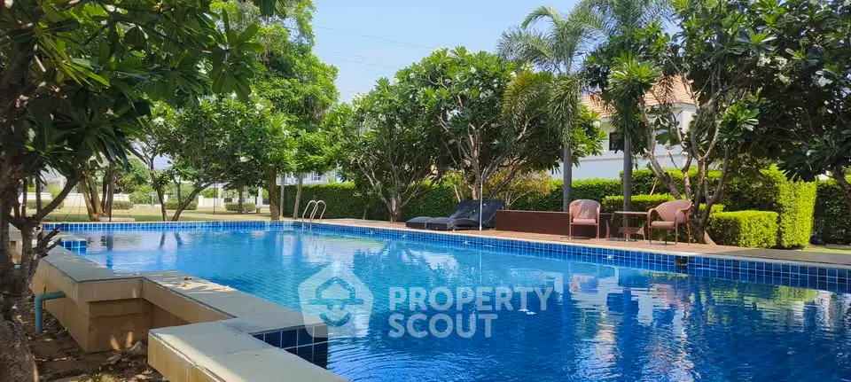 Luxurious outdoor pool surrounded by lush greenery in a serene residential setting.