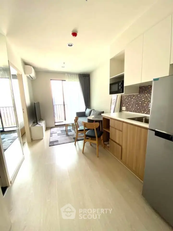 Modern open-plan living room with kitchen, featuring sleek design and natural light.
