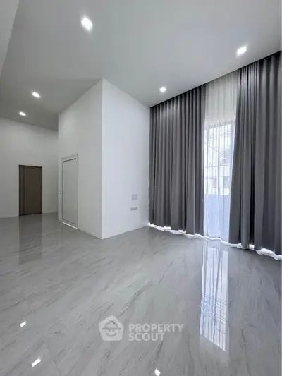 Spacious modern living room with high ceilings and elegant floor-to-ceiling curtains.