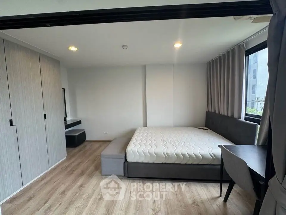 Modern bedroom with large windows and sleek furniture in a stylish apartment.