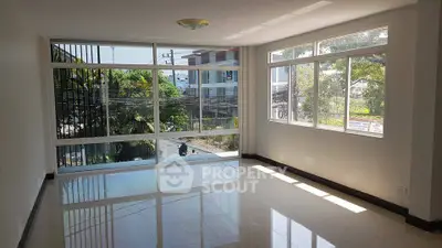 Spacious sunlit room with large windows and glossy tiled floors, perfect for modern living.